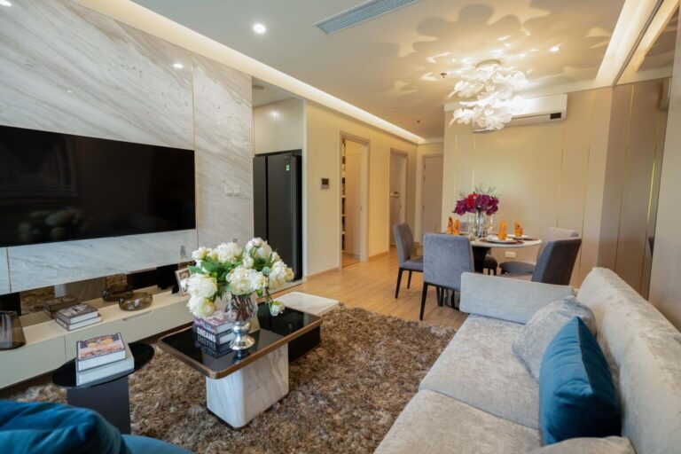 Phòng khách căn hộ mẫu Moonlight 2 với vách TV ốp đá và sofa nỉ
